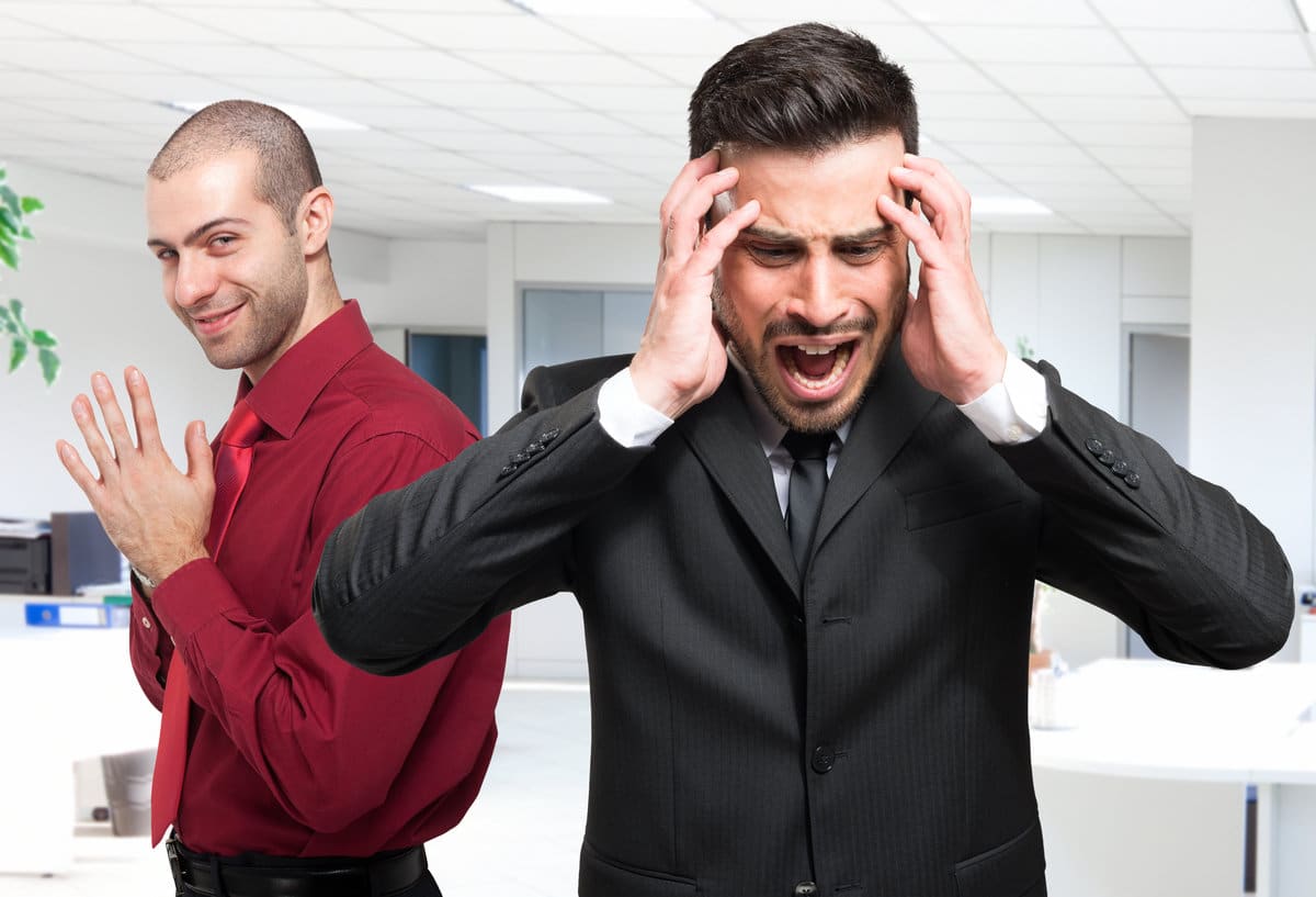 Desperate man in his office. A colleague of him is enjoying his misfortune