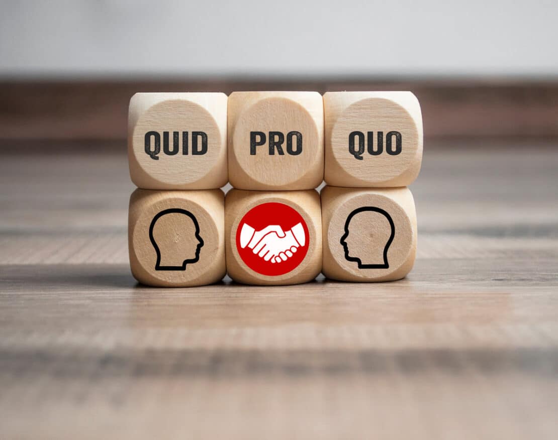 Cubes and dice with business message quid pro quo on wooden background